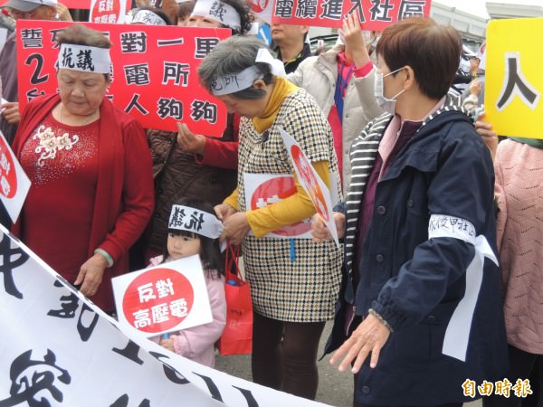 阿嬤為孫子綁上抗議布條，一起走上街頭抗議台電。（記者蔡文居攝）